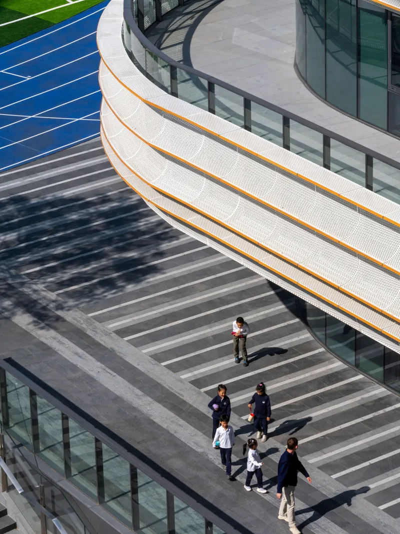 Overhead view of striped plaza with pedestrians walking below curved balcony with orange accent line