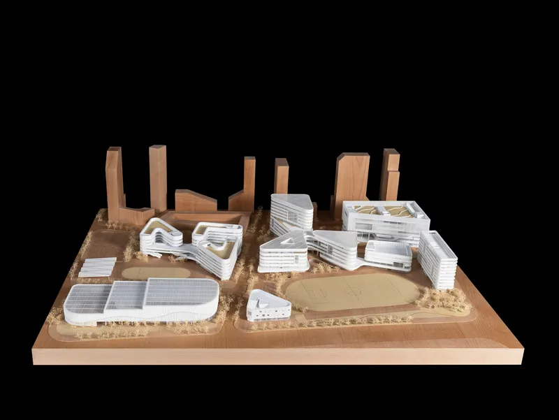 Physical model of a campus with white layered buildings, timber towers, and a central green space