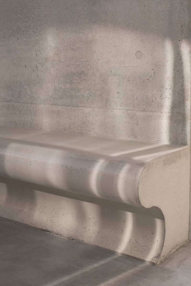 Close-up of board-formed concrete stair treads with dappled sunlight across the surface