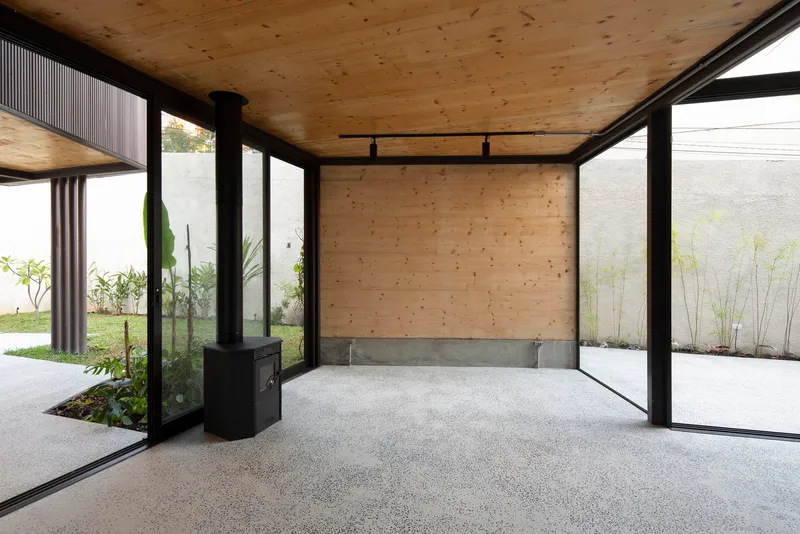 Interior corner with plywood wall, concrete block base and steel-framed glazing overlooking landscaped courtyards