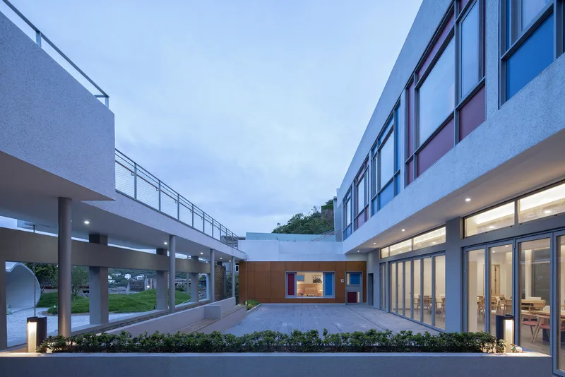 Enclosed courtyard flanked by elevated walkways and glazed volumes under a twilight sky