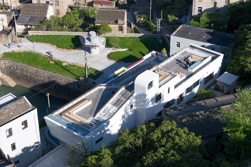 Aerial view of the white roof volumes and central courtyards surrounded by green fields