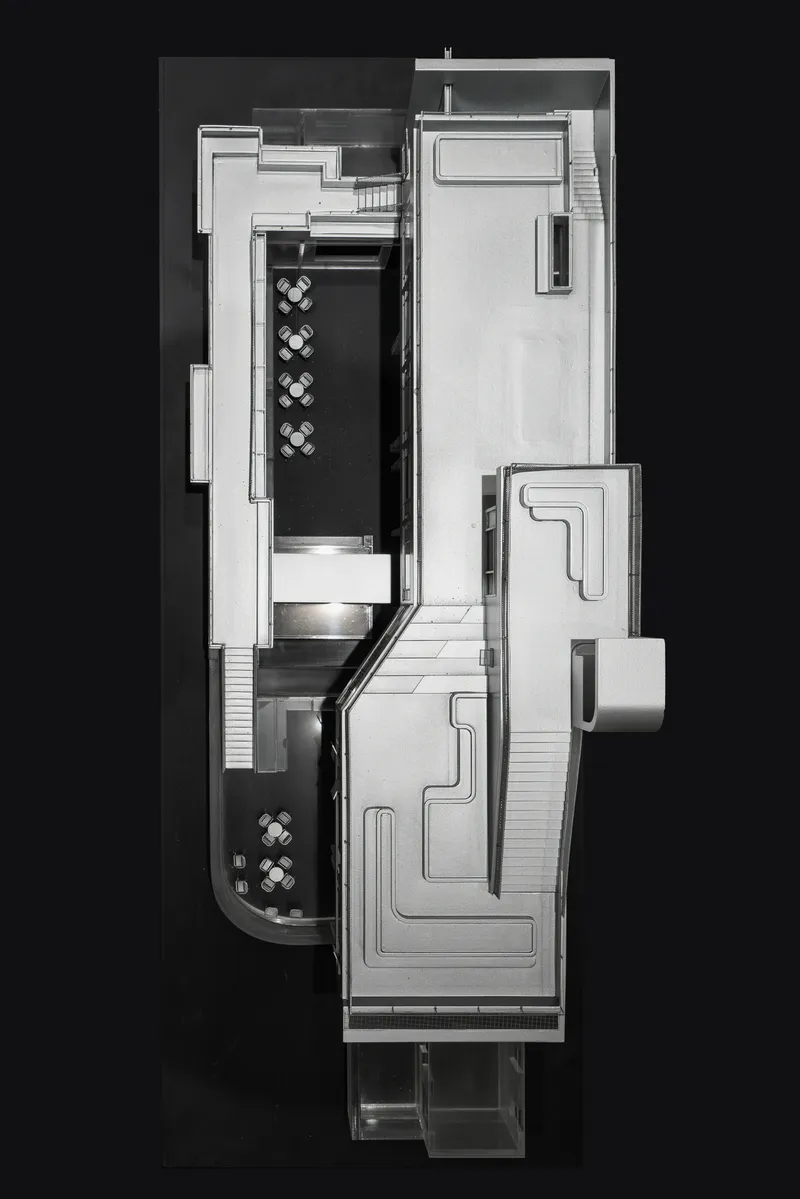 Top-down physical model view showing split-level interior spaces with two dining areas and stairs