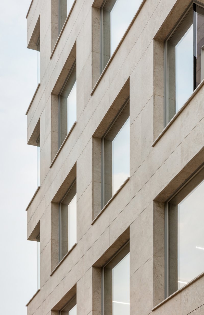 Facade detail showing the vertical rhythm of recessed windows in pale stone panels