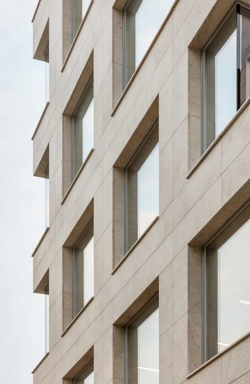 Facade detail showing the vertical rhythm of recessed windows in pale stone panels