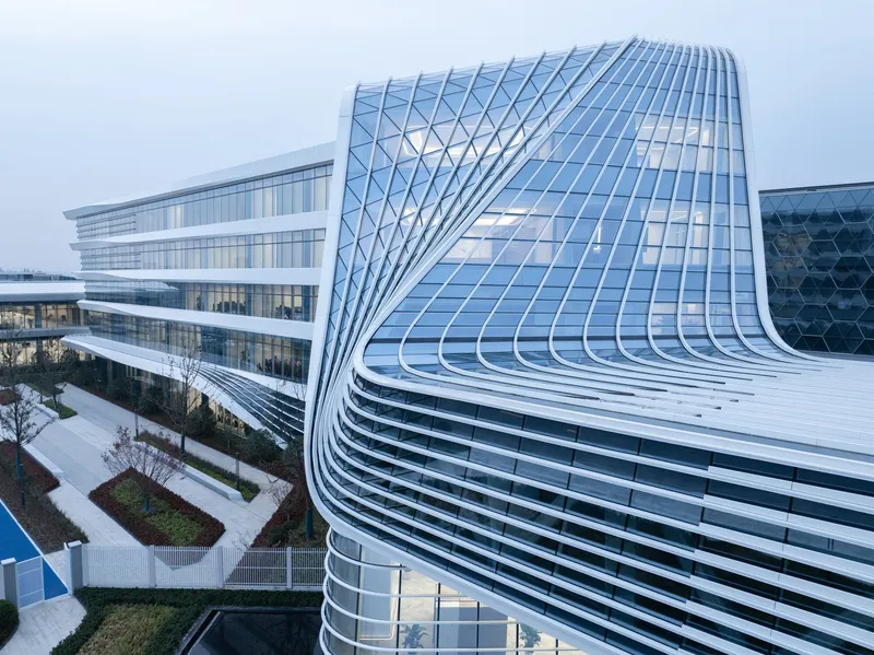 Corner detail of the curved glass curtain wall with diagonal patterning at twilight
