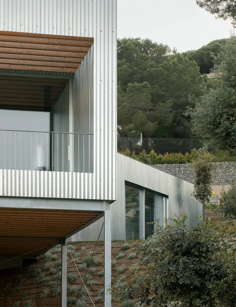 Balcony detail showing corrugated metal cladding and timber soffit above terraced landscaping