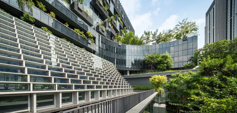 Curved courtyard with layered glass and metal facade panels surrounding planted terraces with mature trees