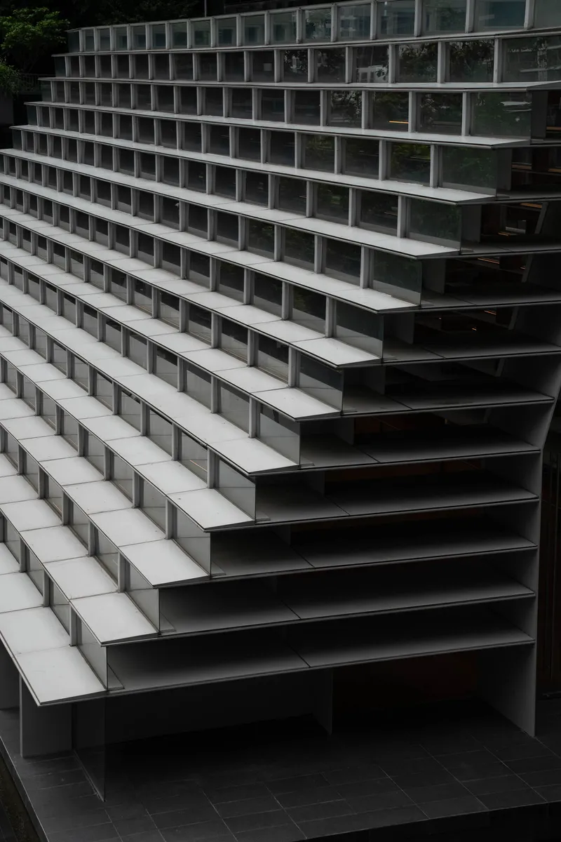 Close-up of terraced seating steps with alternating dark metal risers and pale horizontal treads