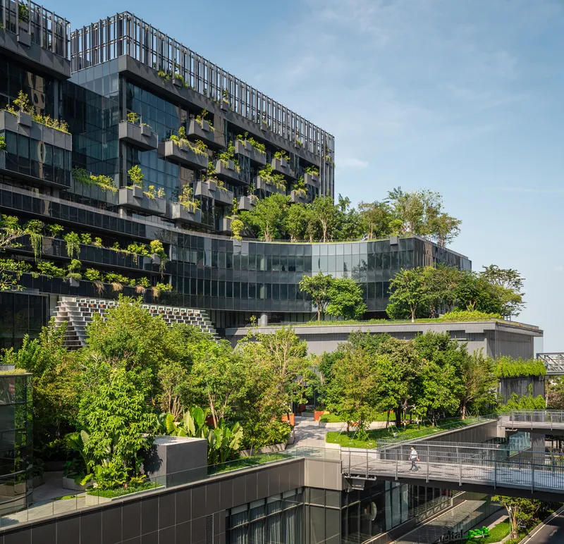 Multilevel planted terraces with trees emerging between glass facades and green roof gardens
