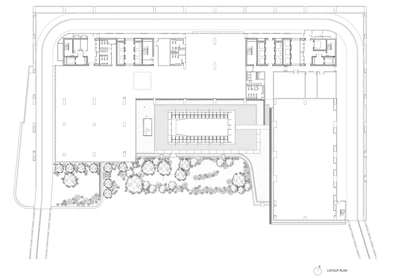 Site plan drawing showing central building with surrounding planted landscape and curved access roads