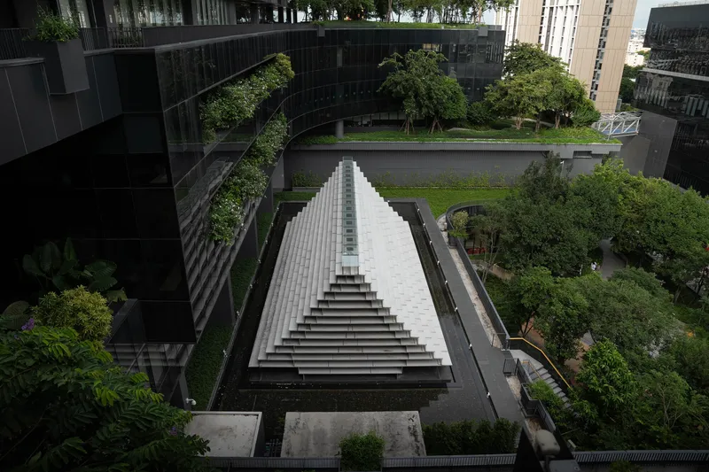 Aerial view of the white stepped pyramid roof structure surrounded by planted courtyards and trees