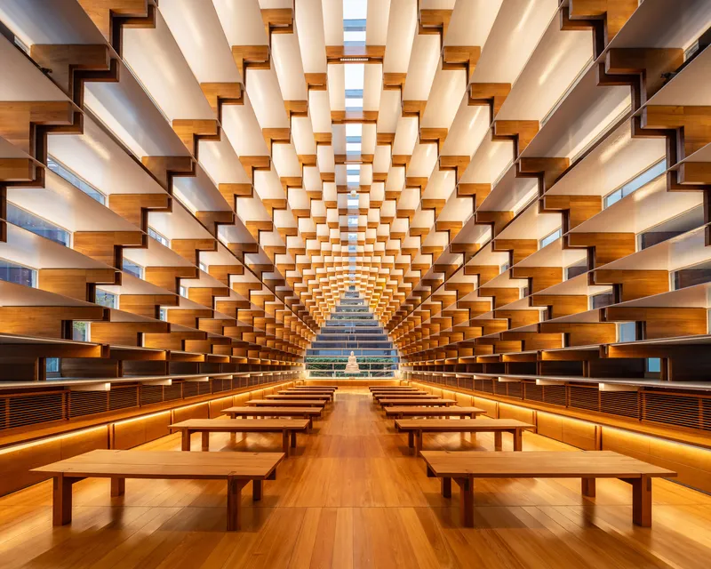 Interior of timber-lined reading room with stepped shelving walls converging toward a glazed pyramidal apex