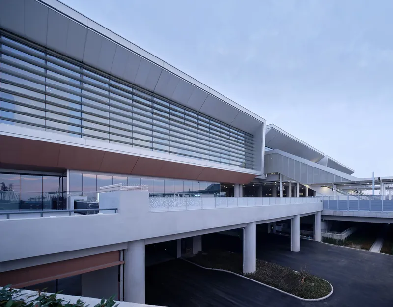 Elevated roadway deck with horizontal louver facade and copper-toned soffit under overcast sky