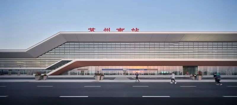 Street facade with horizontal metal fins and angled roofline as pedestrians cross the roadway