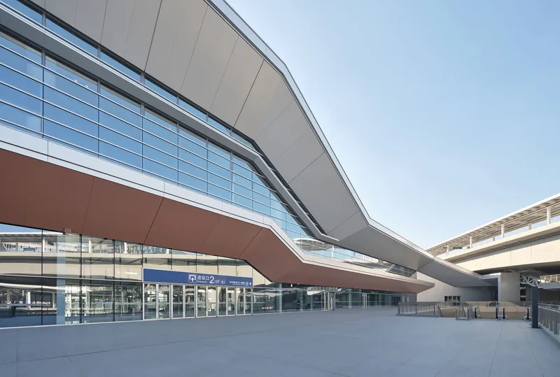 Cantilevered canopy over the glazed entrance plaza with metal soffit and signage visible inside