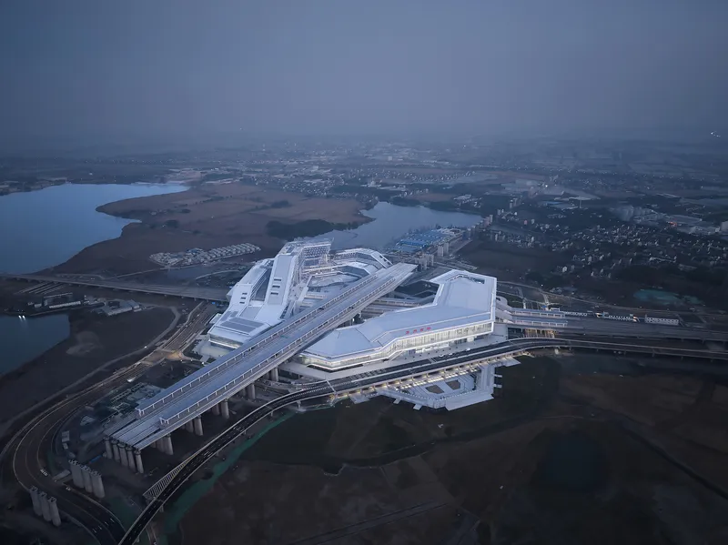 Aerial view of the terminal complex and elevated rail viaduct at twilight with surrounding wetlands