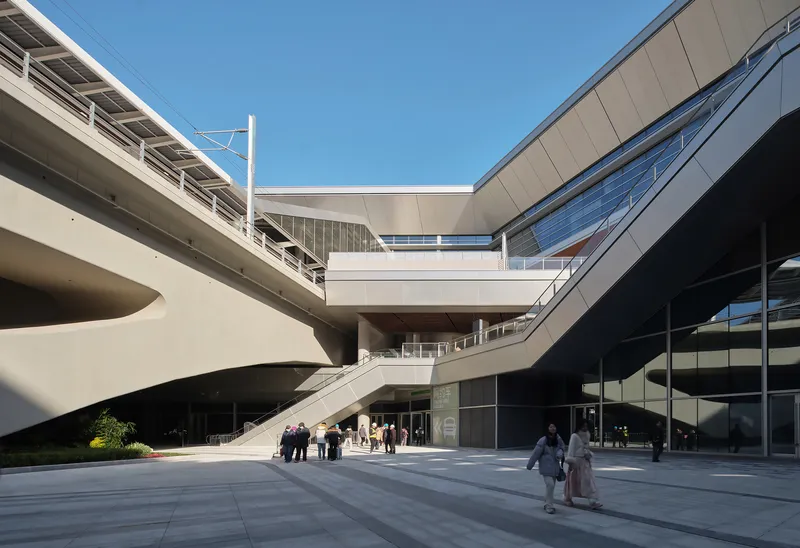 Entry plaza with cascading staircases and pedestrian bridge connecting multiple levels under clear sky