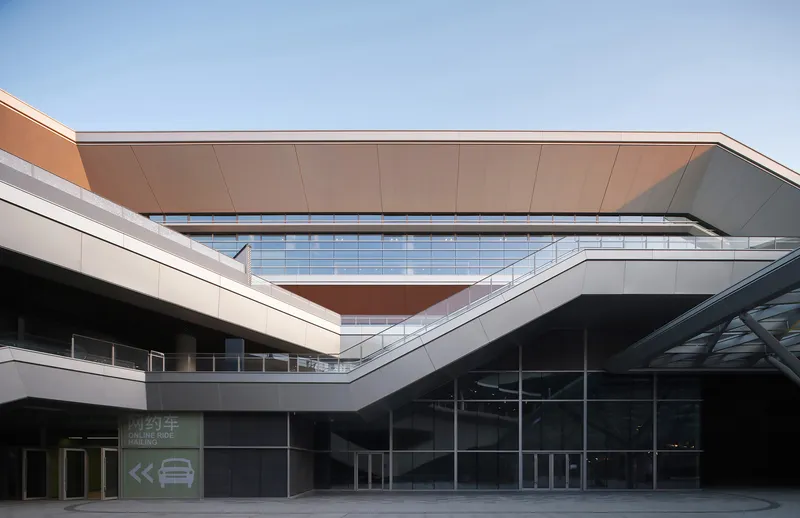 Courtyard view showing layered facades with copper-clad canopy and gridded glass curtain wall