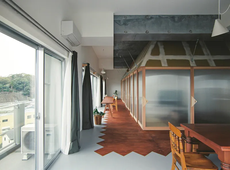 Corridor with zigzag timber flooring, sliding frosted panels, exposed concrete ceiling and full-height glazing with curtains