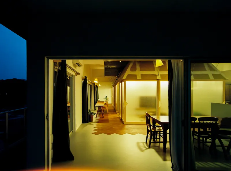 Illuminated interior viewed through open glass doors from exterior terrace at night