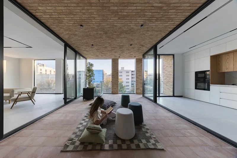 Open-plan interior with terracotta tile floor connecting living spaces and terrace with brick soffit