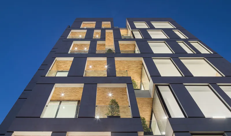 Low angle view of the facade against a clear blue sky showing the grid of openings