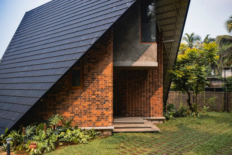 Side elevation showing the shingled roof slope and textured brick wall in afternoon light