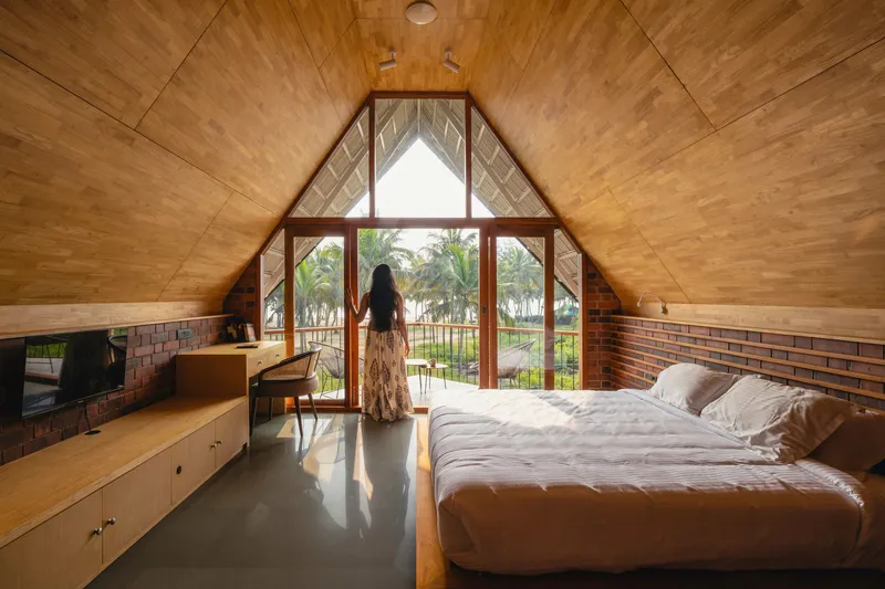 Interior bedroom with timber ceiling, triangular glazed end wall, and person at the glass door
