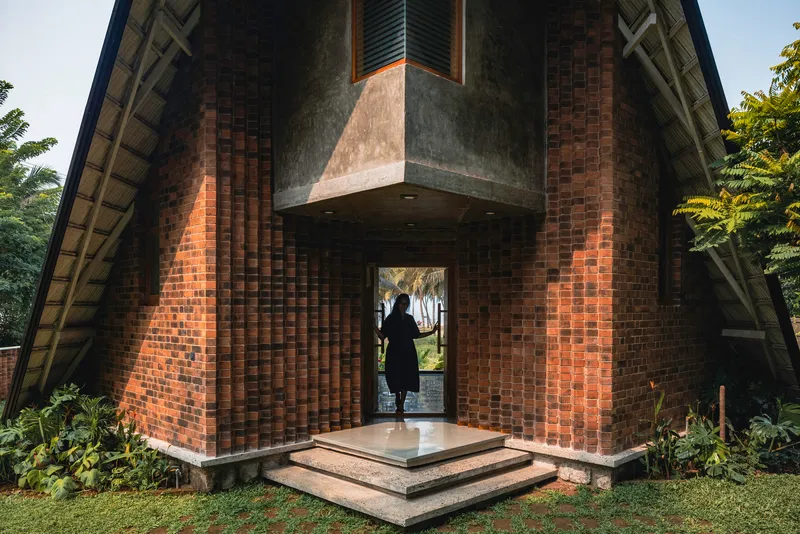 Entry threshold with cantilevered concrete box above doorway and woman standing in the opening
