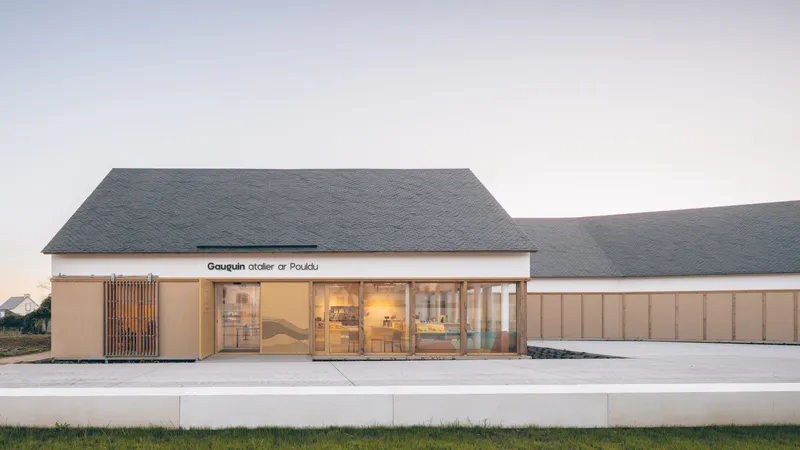 Street-facing facade with timber-clad volumes, glazed entry, and dark slate roofs at dusk