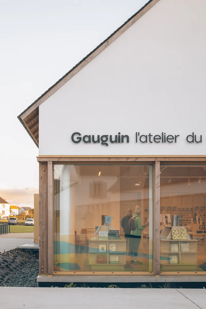 Glazed storefront with timber frame and horizontal striped window decals at dusk