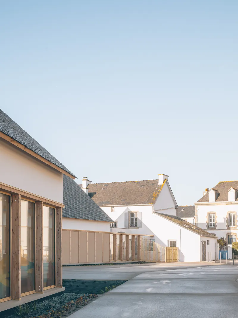 Courtyard view showing gabled volumes with dark slate roofs and timber-clad facades against a clear sky