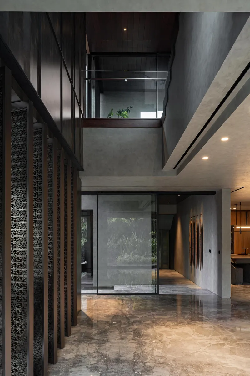 Double-height entrance hall with latticed timber screens and exposed concrete walls