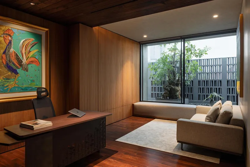 Study with timber-paneled walls and floor-to-ceiling window facing a planted courtyard screen