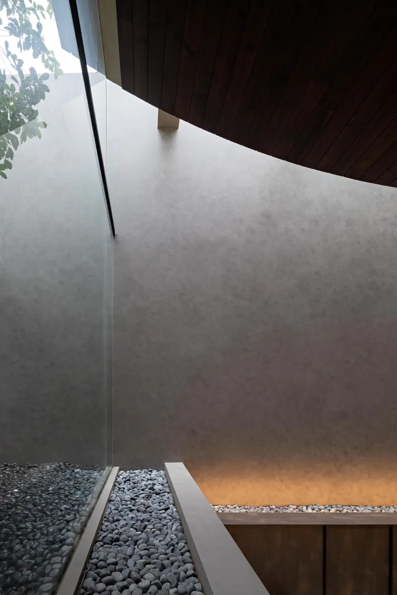 View down into courtyard with polished concrete walls, gravel bed and timber overhang above