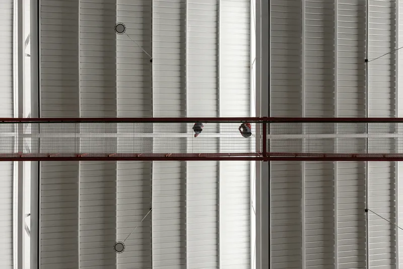 Close-up of horizontal corrugated metal cladding with two red-framed walkways crossing at different levels