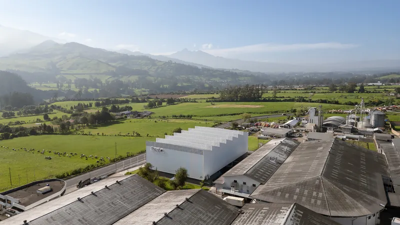 Aerial view of the sawtooth roofline and white corrugated facade set among industrial buildings and farmland