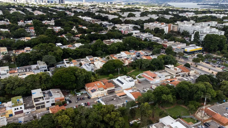 Aerial view of residential blocks with terracotta roofs and white volumes nestled among mature trees