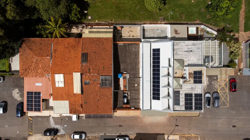 Overhead view of connected houses showing terracotta tile roofs and a new white flat roof volume