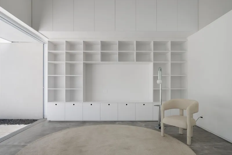 Built-in white shelving unit wrapping the corner with lower cabinets and a clerestory window above