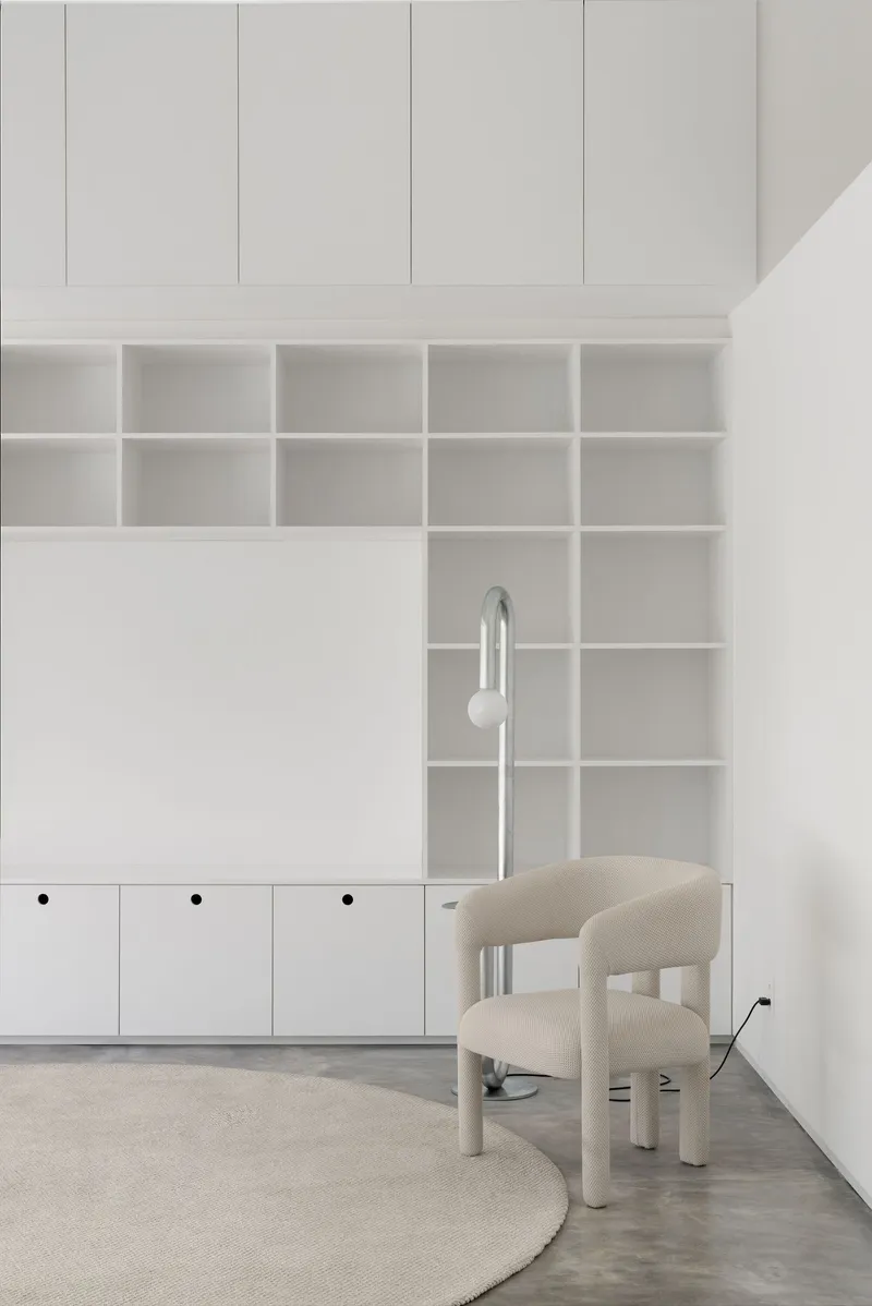 Detail of the white grid shelving with a chrome floor lamp positioned between wall and chair