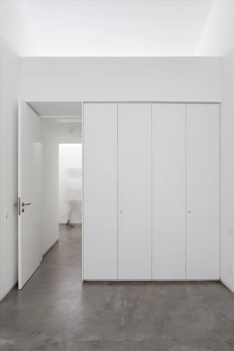 Room with floor-to-ceiling white storage doors and an open doorway revealing an adjacent space