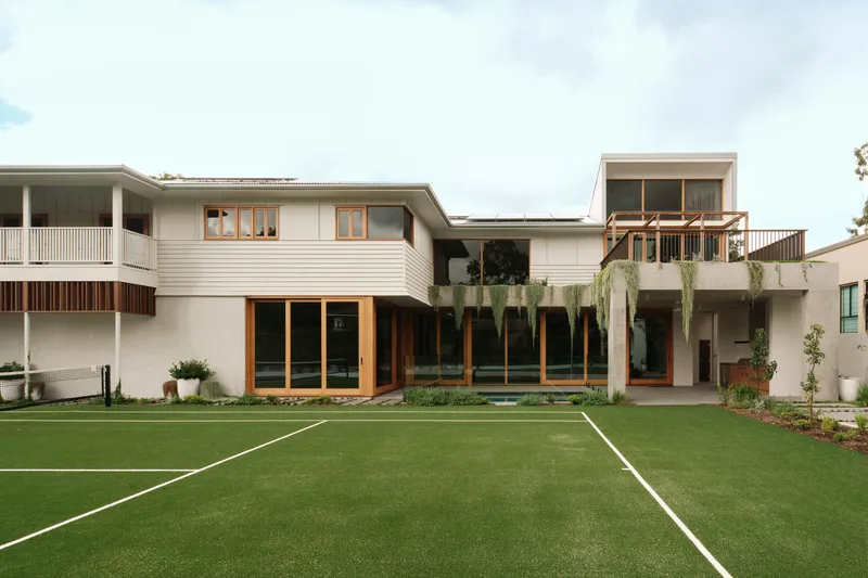 Rear garden view with horizontal weatherboard cladding and timber-framed glazing across linked volumes