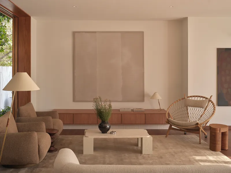 Living room with floor lamp, low timber cabinetry and large canvas hanging on the white wall