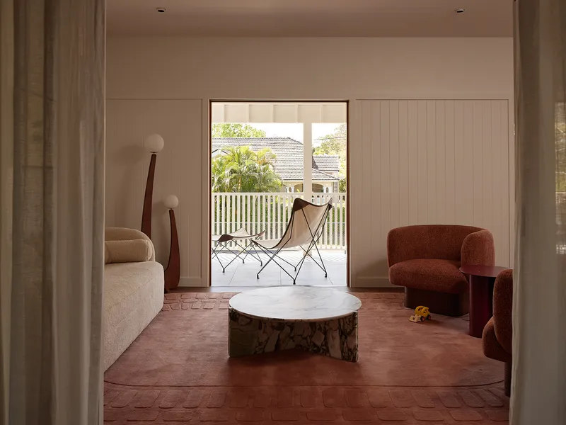 Living room with terracotta parquet floor opening to a timber-railed balcony under daylight