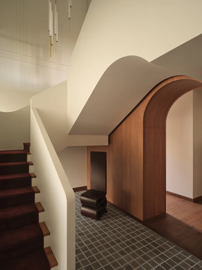 Entry hall with curved timber archway, white plaster staircase and grey mosaic floor tiles