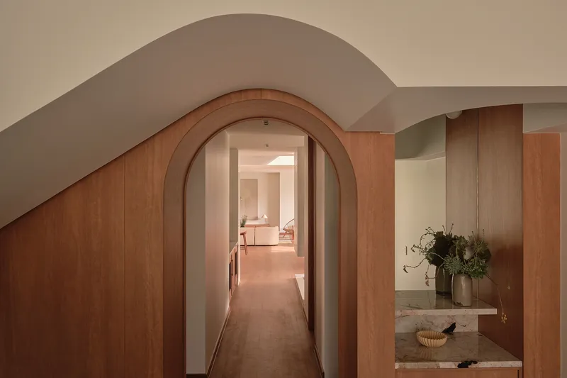 Timber-lined arched doorway leading to a corridor with a vanity niche visible to the right