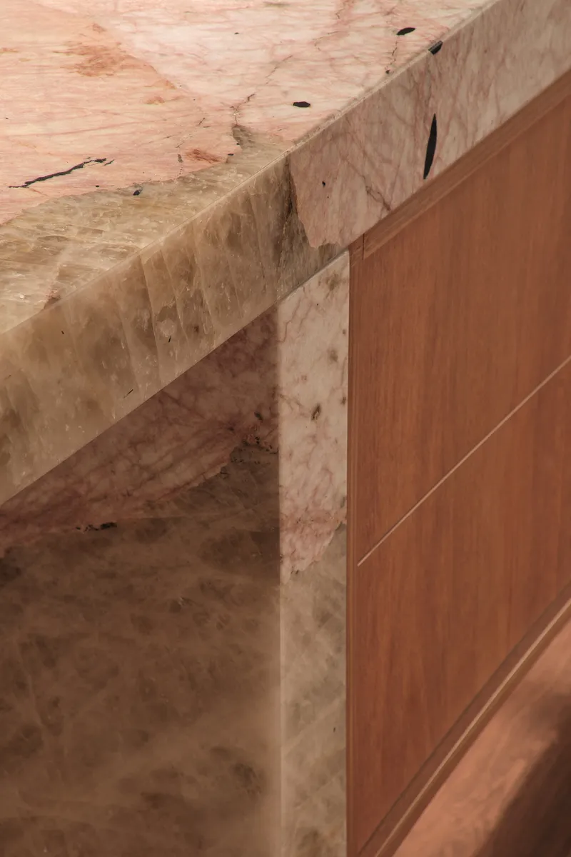 Detail of timber countertop meeting raw plywood cabinetry with visible grain and natural imperfections