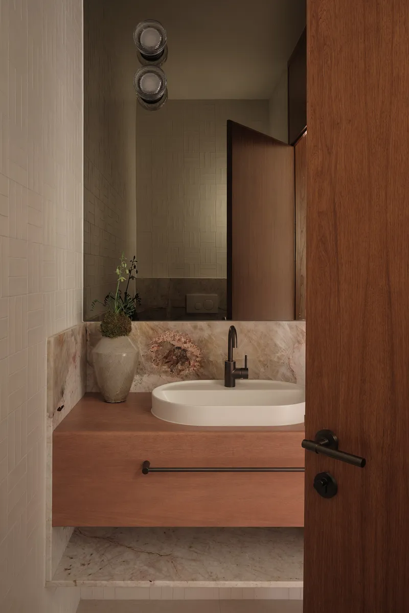 Powder room with floating timber vanity, oval basin, and marbled stone backsplash beneath timber cabinetry